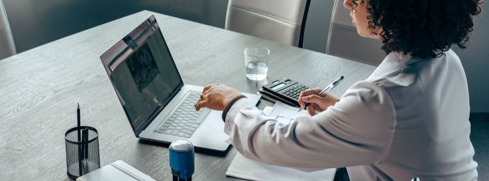 Consultante de FocusTribes travaillant sur un projet de digitalisation avec un ordinateur portable et des documents analytiques sur son bureau