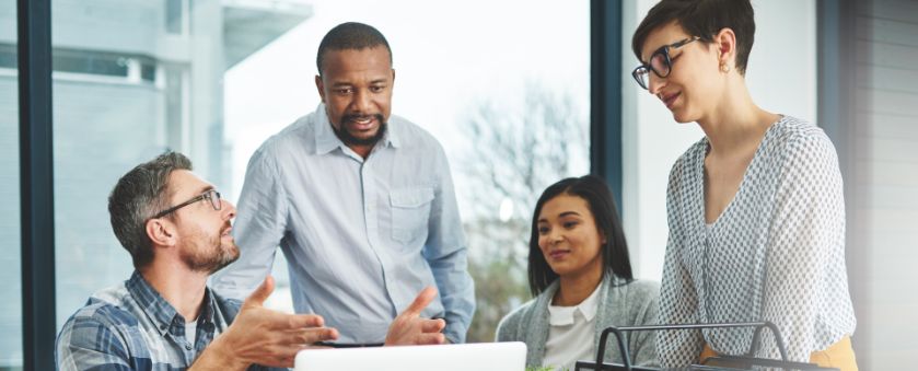 Équipe de conseil en gestion discutant des stratégies de performance opérationnelle autour d'un ordinateur portable dans un bureau lumineux.