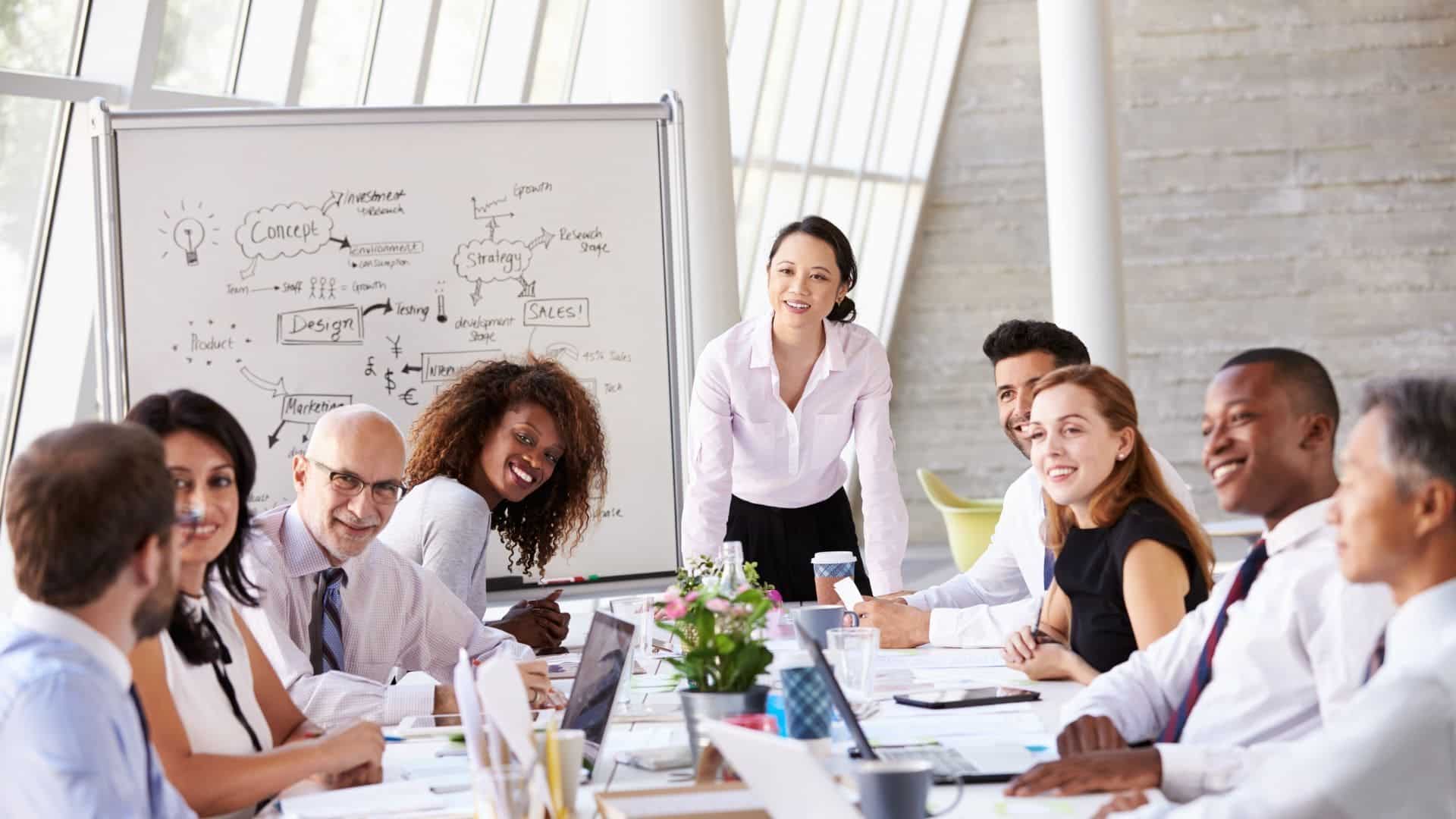 Réunion d’équipe dynamique dans un bureau lumineux, avec une présentation sur tableau blanc et des échanges collaboratifs.