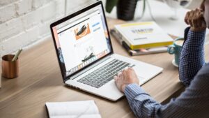 Personne travaillant sur un ordinateur portable avec une tasse de café sur un bureau moderne, analysant une page web de e-commerce.