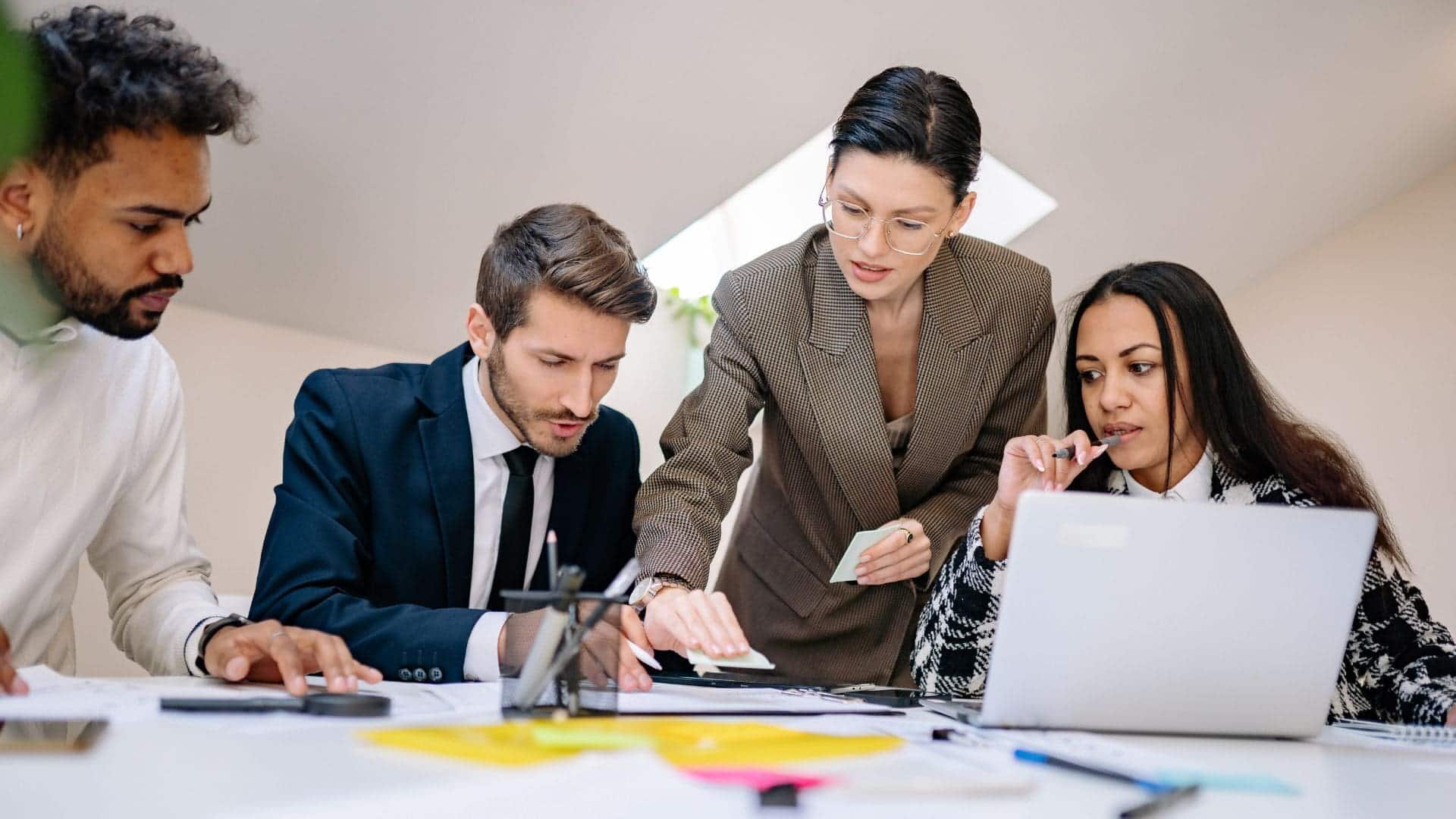 Équipe de professionnels en réunion, échangeant des idées autour d’un bureau avec un ordinateur portable et des documents.